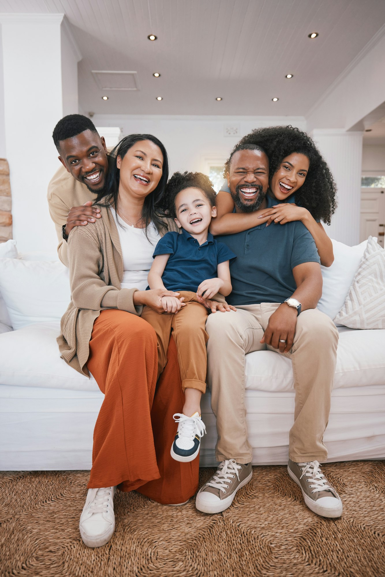 Happy, portrait and family generations on a sofa hugging in the living room of modern house. Love,